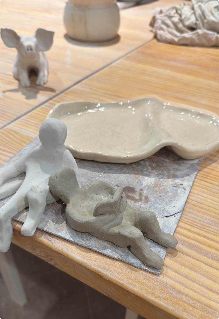 Clay figure lying down, next to a ceramic plate
